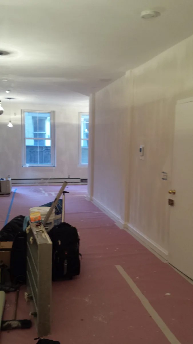 Wall and ceiling preparation with protected flooring in a Manhattan loft.