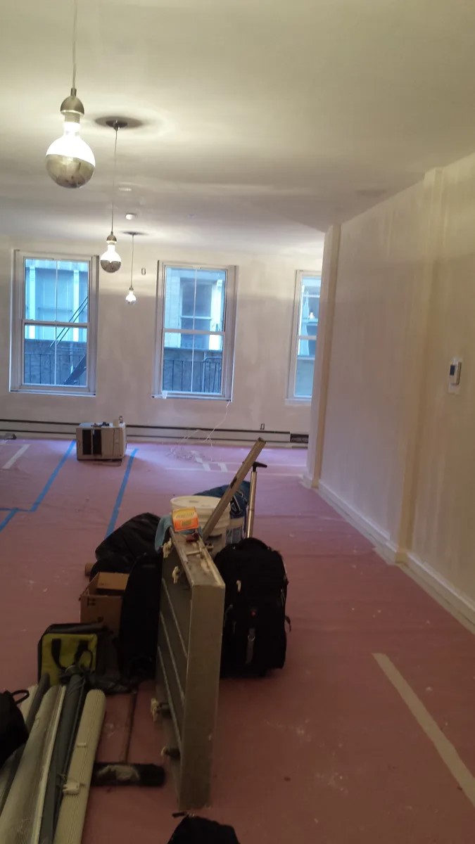 View toward loft windows with protected flooring and painting preparation tools.
