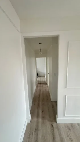 Hallway with light-toned flooring, white walls and trim during a Corniel apartment renovation in Manhattan.