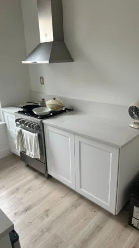 Kitchen range, stainless steel hood and white base cabinets before cabinet hardware installation.